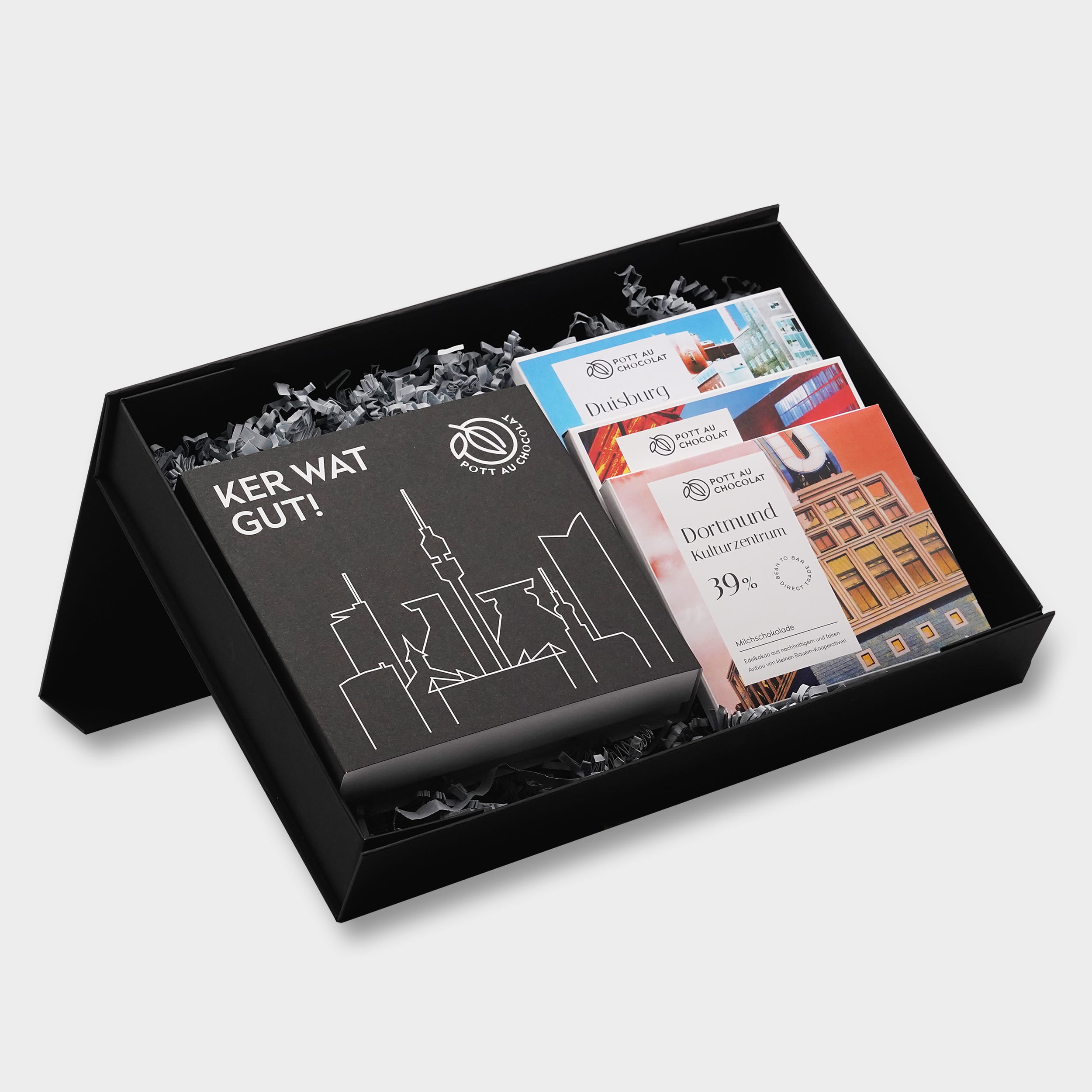 Geschenkbox mit verschiedenen Produkten von Pott au Chocolat: Eine Pralinenbox und drei verschiedene Tafeln Schokolade in Verpackung mit Ruhrgebiet-Design