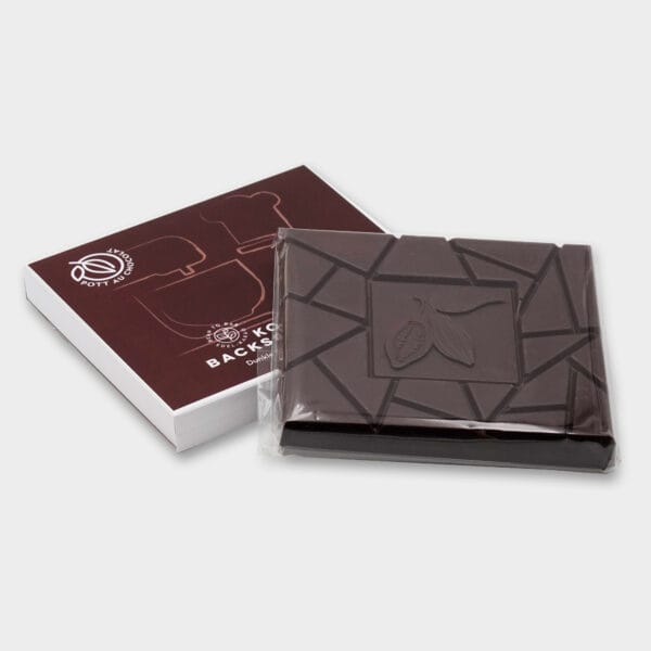 Koch- und Backschokolade offen und mit geschlossener Verpackung. Design mit weißen Illustrationen von Backsachen wie Schneebesen und Kochmütze auf braunem Hintergrund