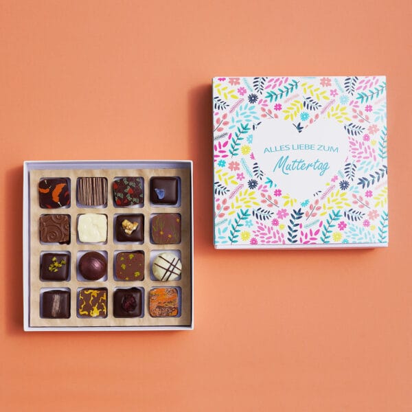 Pralinenbox mit 'Alles Liebe zum Muttertag' Motiv mit Blumen und Herz in blau, gelb und pink. Daneben die geöffnete Box mit 16 bunt dekorierten Pralinen.