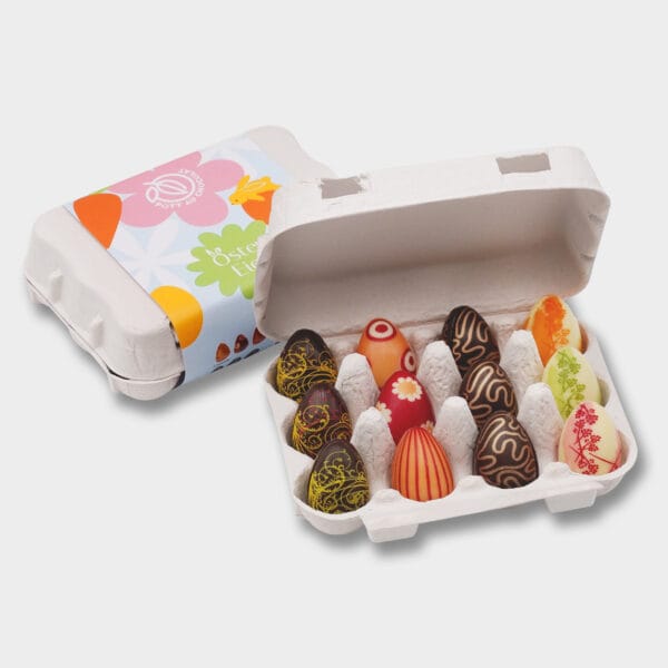 Geöffnete Verpackung von Schokoladen-Ostereiern von Pott au Chocolat: Natürlicher Karton, ähnlich einem echten Eierkarton, nur kleiner. Darin bunte Schokoladen-Ostereier mit verschiedenen Mustern wie Streifen, Blumen, Punkten und mehr
