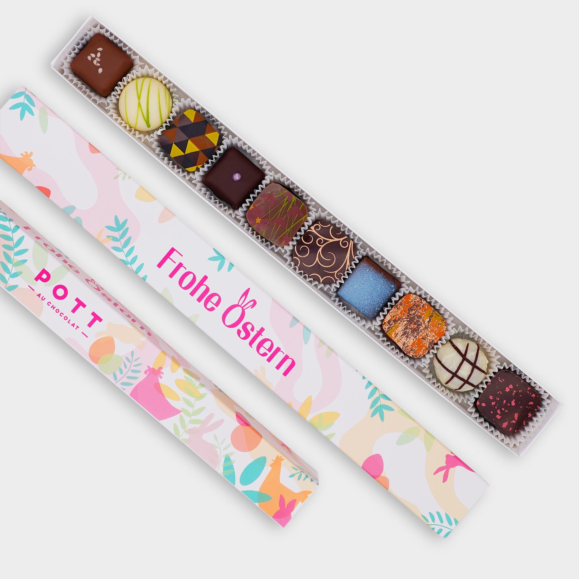Pralinenstange mit 10 Pralinen auf der bunten Pastellfarbenden Verpackung steht Frohe Ostern. Die Pralinen sind buntverzieht mit Dunkler, Milch und weißer Schokolade.