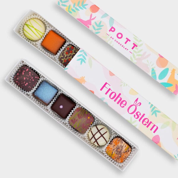 Pralinenstange mit 6 Pralinen auf der bunten Pastellfarbenden Verpackung steht Frohe Ostern. Die Pralinen sind buntverzieht mit Dunkler, Milch und weißer Schokolade.