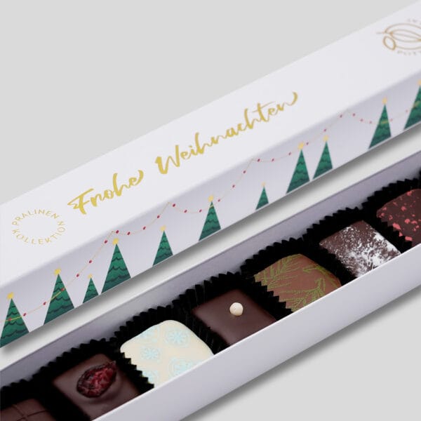 Detail der Pralinenstange mit 10 bunt dekorierten Pralinen in weiß mit Weihnachtsmotiv. In gold geprägt 'Frohe Weihnachten' und Bäumchen.