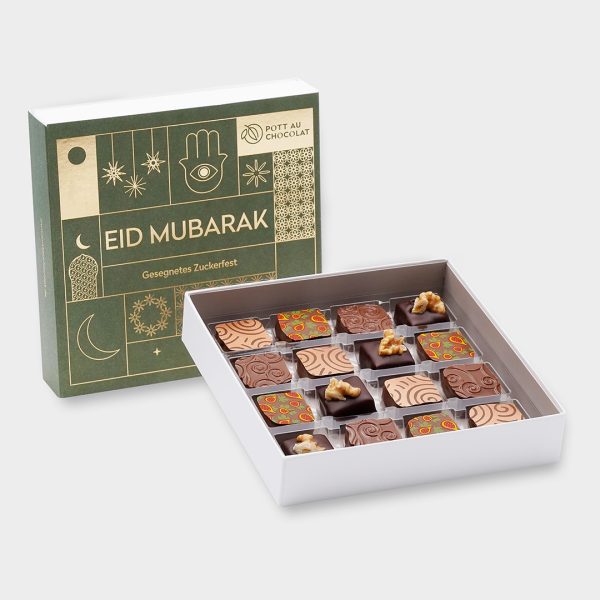 Pralinenschachtel Eid Mubarak. Banderole in grün mit goldener Prägung. Davor steht eine geöffnete Pralinenschachtel mit 16 bunt dekorierten Pralinen