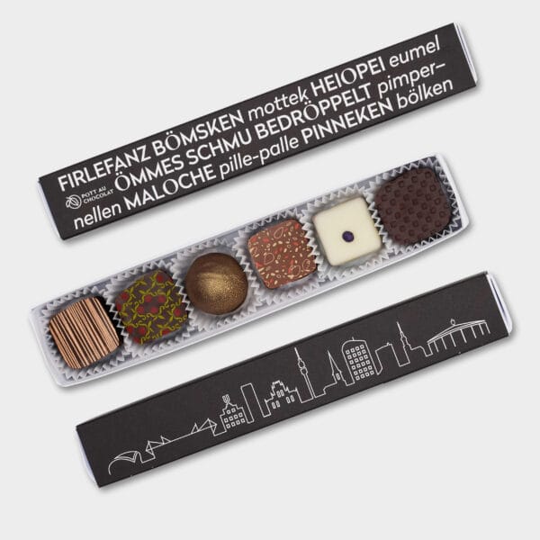 Pralinen Stange in schwarz mit Skyline von Dortmund und Ruhrgebiet Wörtern, wie 'Filefanz, Heiopei, pille-palle' und weiteren. Davor eine geöffnete Pralinenstange mit 6 bunt dekorierten Pralinen.