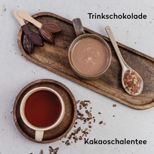 Eine Tasse mit Trinkschokolade und eine Tasse mit Kakaoschalentee im Vergleich nebeneinander. Dabei Kakaoschalen und Trinkschokolade am Stiel.