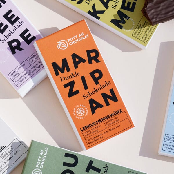 Mehrere Verpackungen der gefüllten Tafeln – Sorten wie Marzipan, Whisky, Salzkaramell, Himbeere und mehr. Die Verpackungen sind bunt gestaltet in Orange, Hellblau, Gelb, Dunkelgrün und Rosa.