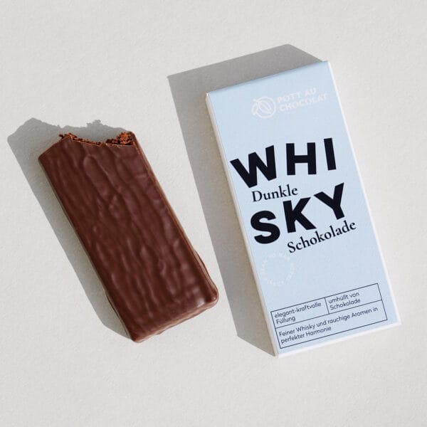 Gefüllte Tafel aus dunkler Schokolade. Daneben die Verpackung mit der Aufschrift 'Whisky'. Die Aufschrift ist verspielt mit tanzenden Buchstaben gestaltet. Farben des Designs: Hellblau, Schwarz und Weiß