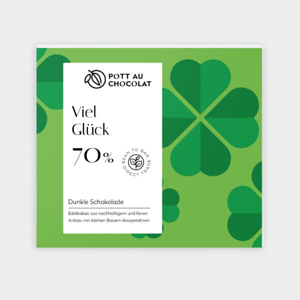 Verpackung unserer dunklen Motto Schokolade "Viel Glück". Hellgrüner Hintergrund mit grafisch dargestellten grünen vier blätterigen Kleeblättern darauf ein weißes Rechteck mit der Bezeichnung und unserem Logo