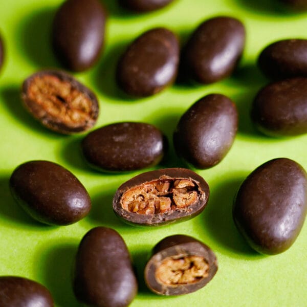 Kakaobohnen in Schokolade. Einige sind aufgeschnitten, sodass die Kakaobohnen im Inneren der Schokoladenhülle sichtbar sind